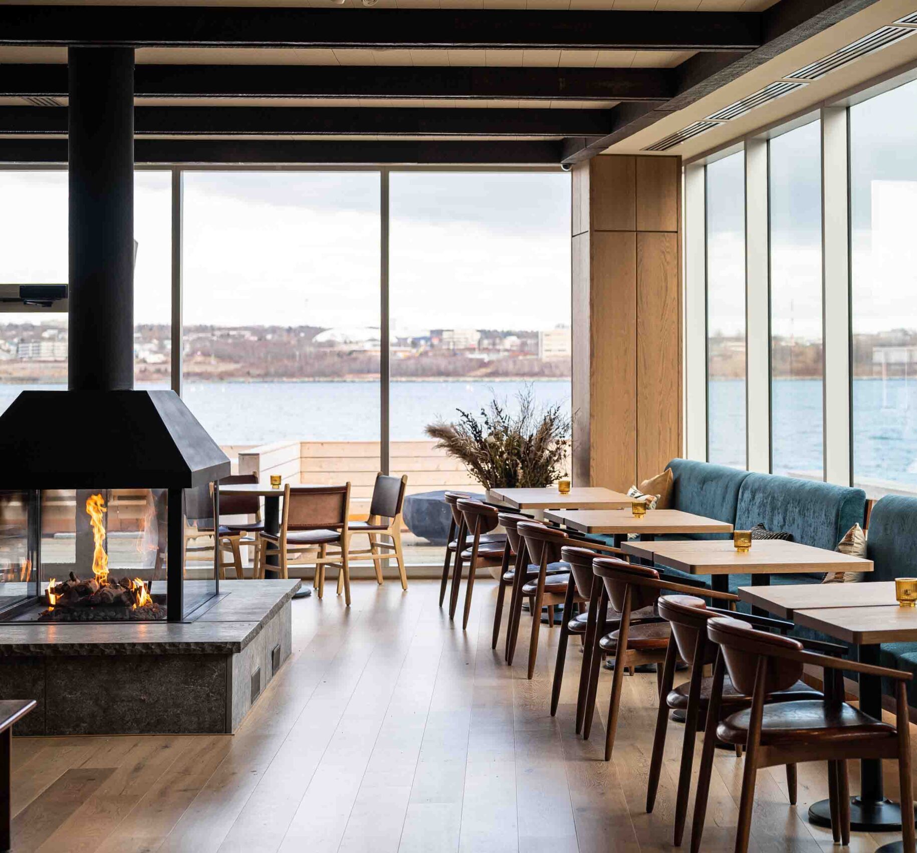 wide interior shot of salt and ash dining area with dark wooden chairs and large windows beside halifax waterfront