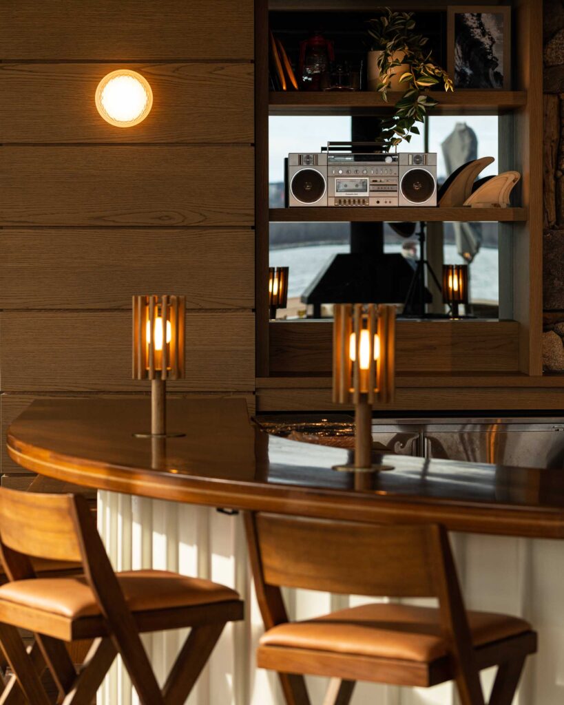a warmly lit bar with curved bar top and vintage radio at salt + ash beach house